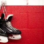 Zwei Bauer Schlittschuhe haengen mit den Senkeln an einem Haken vor einer roten Kabinenwand